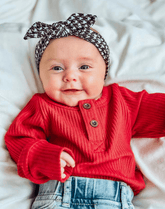 Little girl is wearing a comfortable baby headband for little girls from By Bella Boutique.